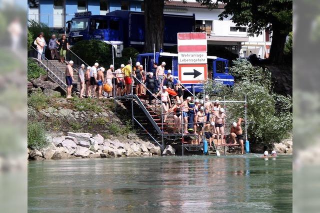 Mit weier Badekappe schwimmen sie im Rhein