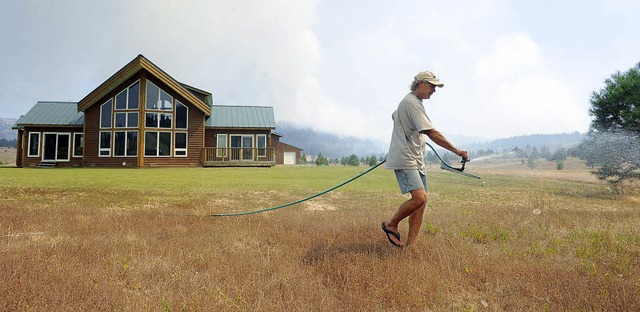 Mit Rasensprenklern versucht Rod Pears... Seattle vor den Flammen zu schtzen.   | Foto: dpa