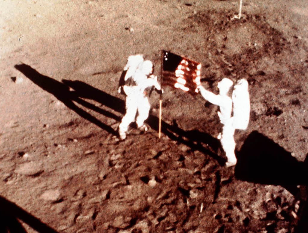 Armstrong und Aldrin auf dem Mond.  Dort setzen sie nicht nur eine US-Flagge, sondern enthllen auch eine Gedenkplakette.