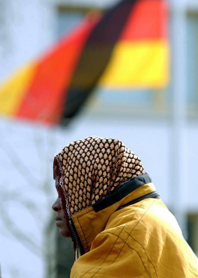 Eine Asylbewerberin sitzt unter einer Deutschlandfahne.  | Foto: dpa