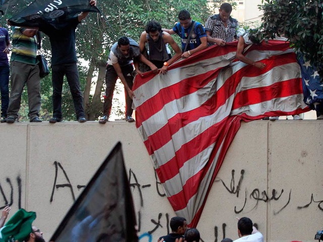 Aufgebrachte Islamisten reien die US-Flagge herunter.  | Foto: dpa