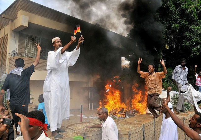 Ein Demonstrant zndet auf dem Gelnde...t in Khartoum ein deutsche Flagge an.   | Foto: AFP
