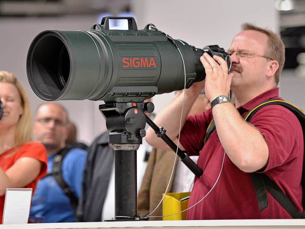 Ein Mann schaut durch ein Riesen-Teleobjektiv.