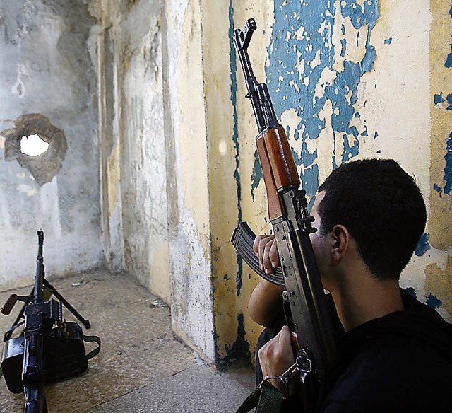 Ein Hisbollah-Kmpfer kontrolliert von...em Versteck aus ein Viertel in Beirut.  | Foto: afp