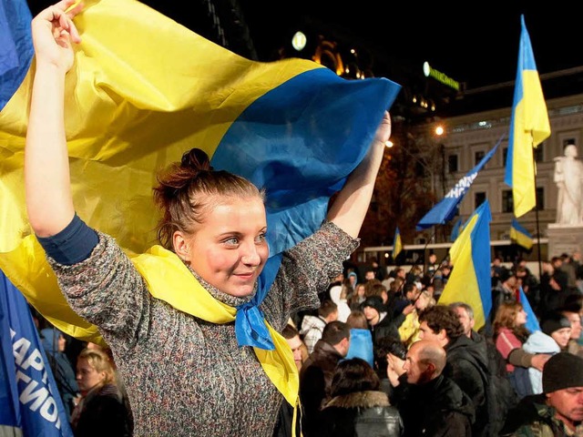 Eine junge Frau schwingt die ukrainisc...er Regierungspartei organisiert wurde.  | Foto: dpa