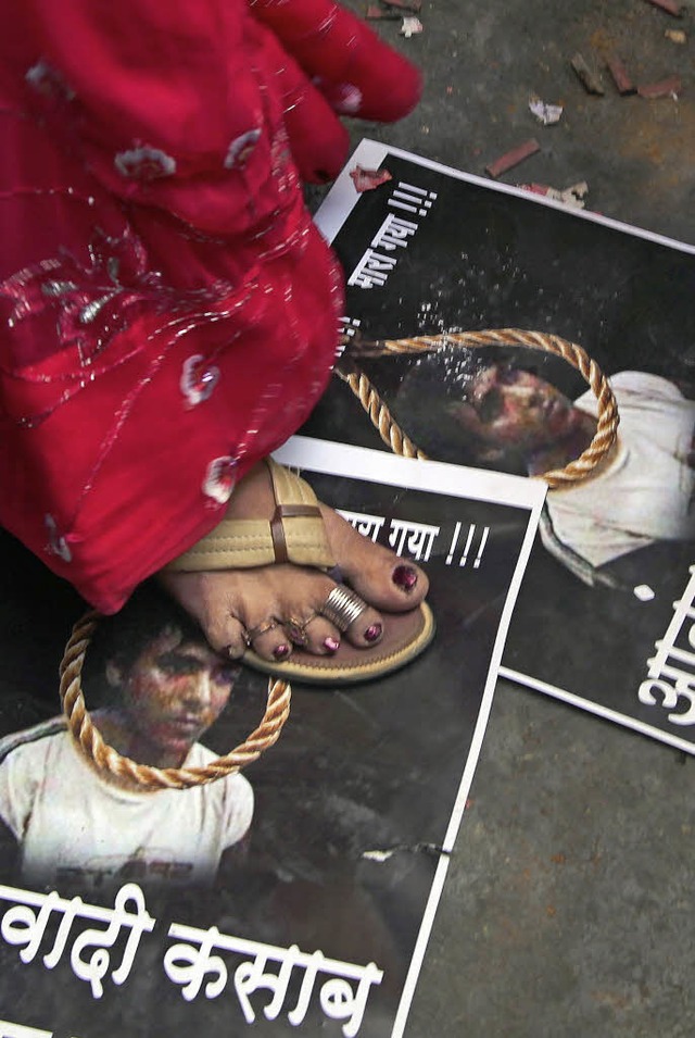 Eine Inderin trampelt auf Bildern des Attentters herum.   | Foto: DPA