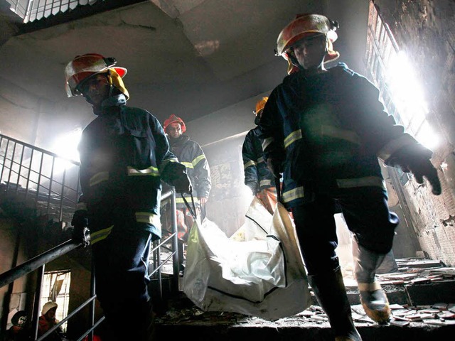 Feuerwehrmnner tragen eine Leiche aus dem Gebude.  | Foto: dpa