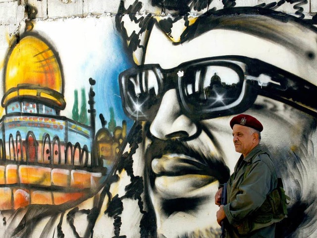 Ein palstinensischer Sicherheitsbeamter steht vor einem Arafat-Graffiti.  | Foto: AFP