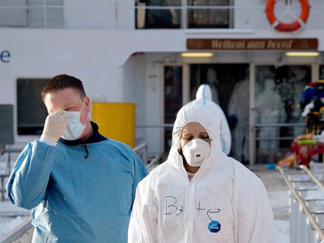 Hilfskrfte in Schutzanzgen stehen in... einem Kreuzfahrtschiff auf dem Rhein.  | Foto: dpa