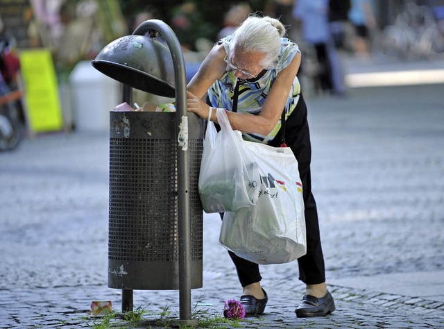 Im Mlleimer sucht eine ltere Frau nach Pfandflaschen.   | Foto: dpa