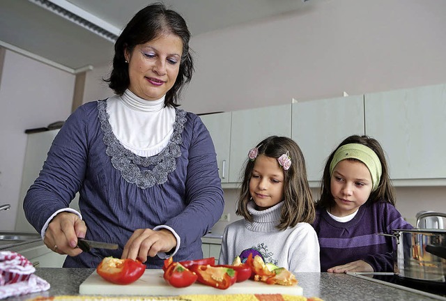 Heike Foster bereitet das Mittagessen zu, Nathalie und Larissa schauen zu   | Foto: Christoph Breithaupt