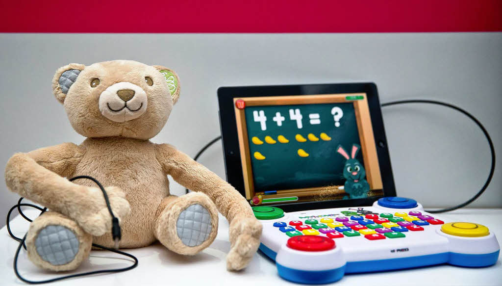 Ein Teddy mit einem Kabelanschluss fr einen integrierten Lautsprecher sowie eine Tastatur fr Kleinkinder, die an ein Tablet-PC angeschlossen ist.