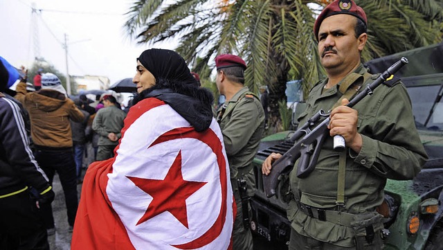 Eine Frau, gehllt in die Flagge Tunes...tet den Trauerzug fr  Chokri Belad.   | Foto: AFP