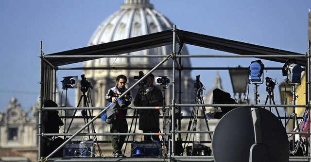 Ein Fernsehteam baut auf einem Dach vor dem Petersdom seine Ausrstung auf.   | Foto: AFP