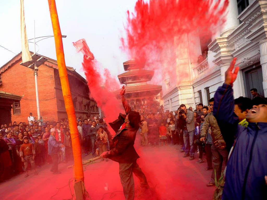 Rotes Pulver regnet beim Holi Festival in Nepal auf die Kpfe der Versammelten.