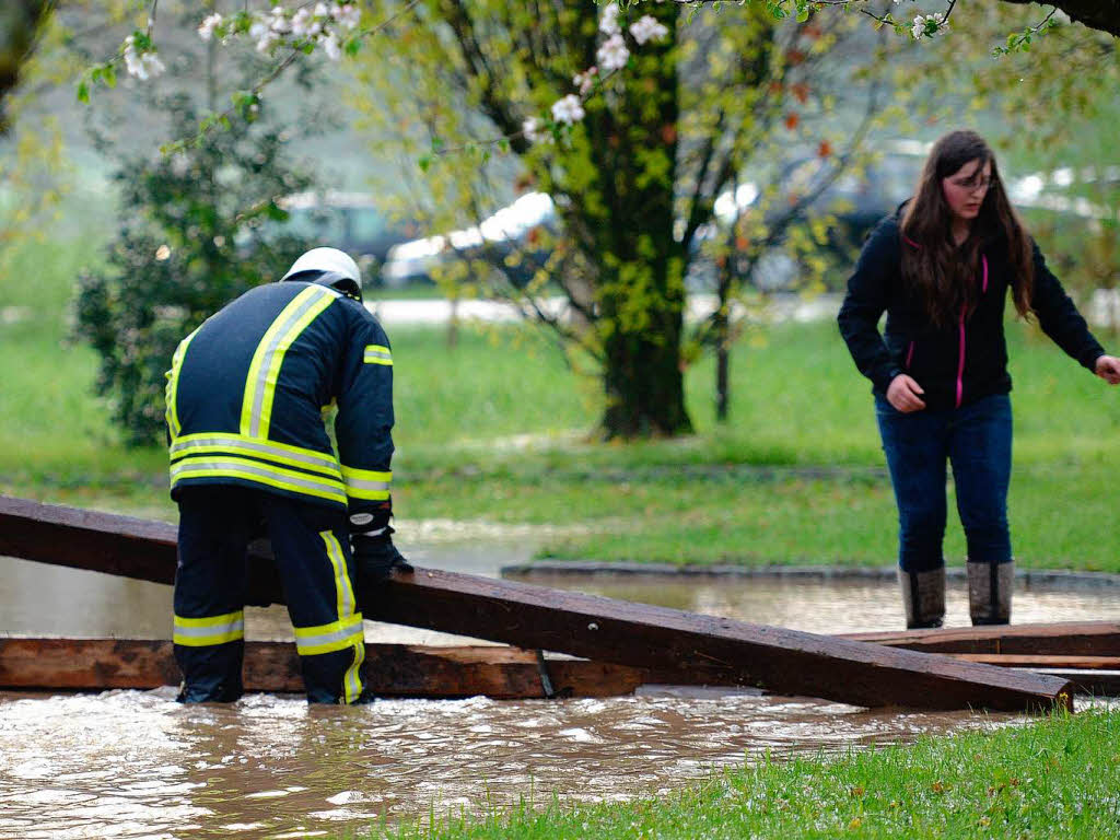 Ein Feuerwehrmann und eine Frau versuchen am 02.05.2013 in Gutach mit Balken Wassermassen aufzuhalten.