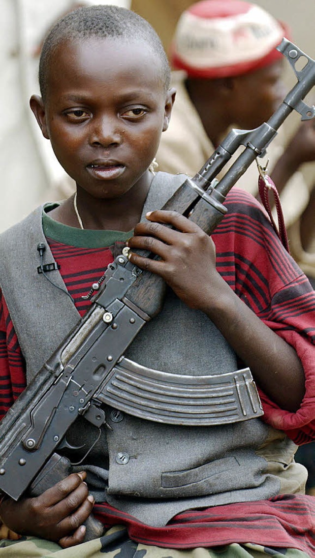 Mit einer Waffe in der Hand bewacht ei...ger Kindersoldat eine Strae im Kongo.  | Foto: DPA