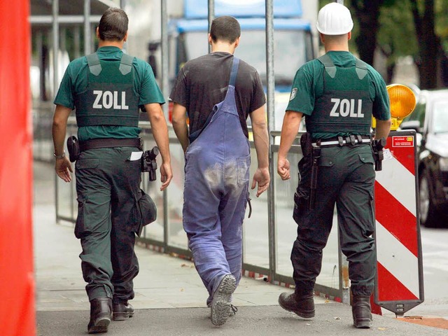 Zollbeamte begleiten einen Arbeiter zur  Befragung.  | Foto: dpa