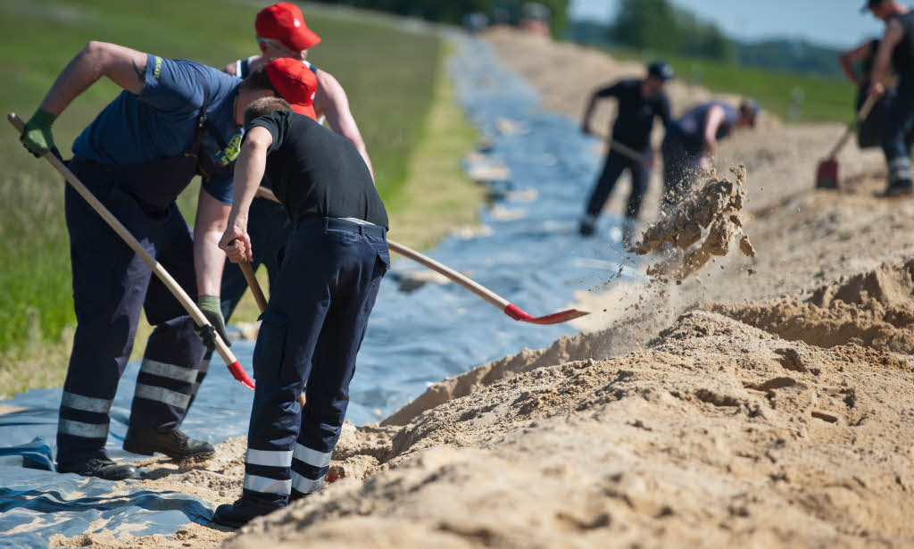 Helfer bauen  bei Hitzacker (Niedersachsen) einen zustzlichen Damm aus Sand und Folie auf dem Elbdeich.