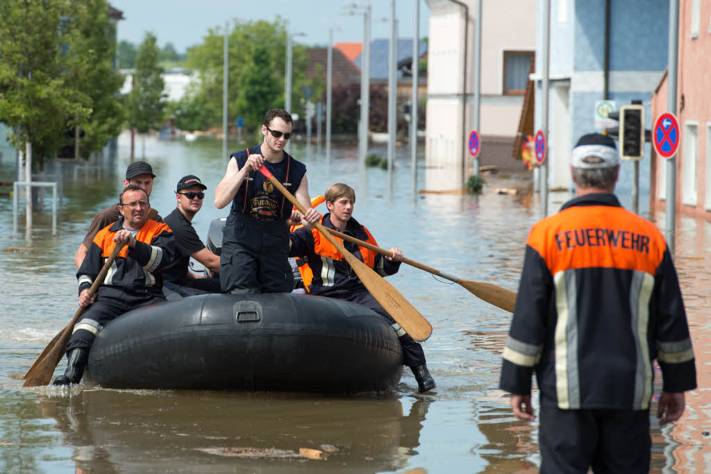 Rettungskrfte fahren  mit einem Schlauchboot durch eine berflutete Strae im Deggendorfer Ortsteil Fischerdorf