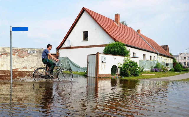 Ein Radfahrer fhrt in Wust (Sachsen-A...e von Hochwasser berfluteten Straen.  | Foto: dpa