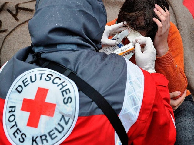 Eine Sanitterin des Deutschen Roten K...in Berlin einem Mann einen Verband an.  | Foto: dpa