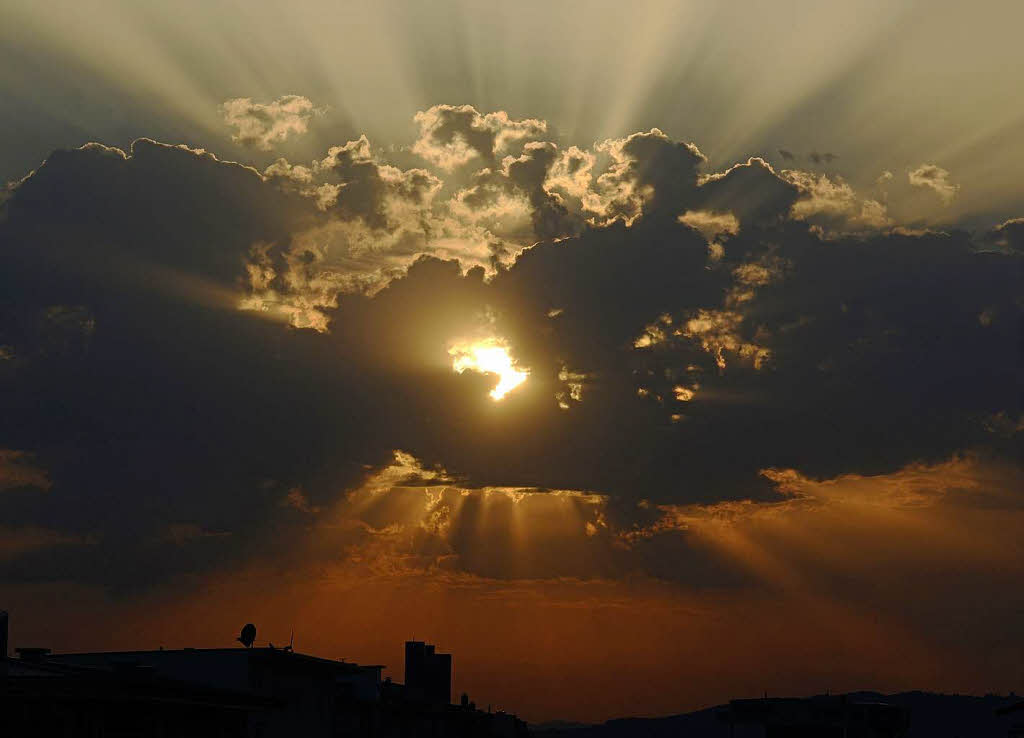 Die Sonne geht in Freiburg hinter Wolken unter.