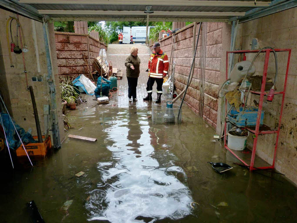 Vor ein paar Tagen htte man hier noch nicht stehen knnen – die Frau zeigt den Wasserstand in der Einfahrt.