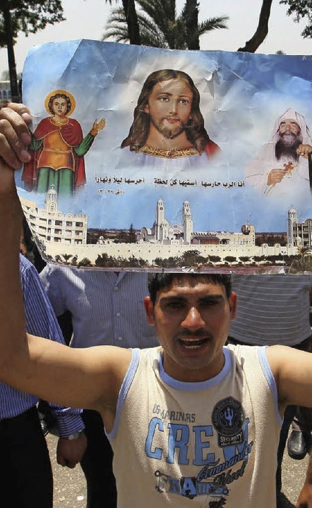 Ein koptischer Christ hält bei einer D...m Bild von Jesus Christus in die Höhe.  | Foto: dpa