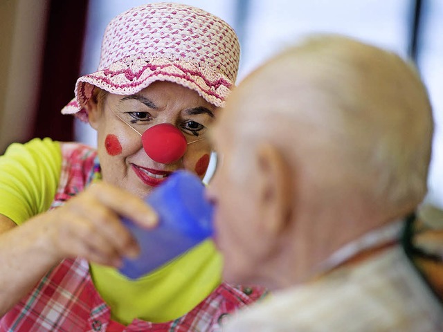 Eine als Clown verkleidete Mitarbeiter...em Pflegeheim mit einem Demenzkranken.  | Foto: dpa