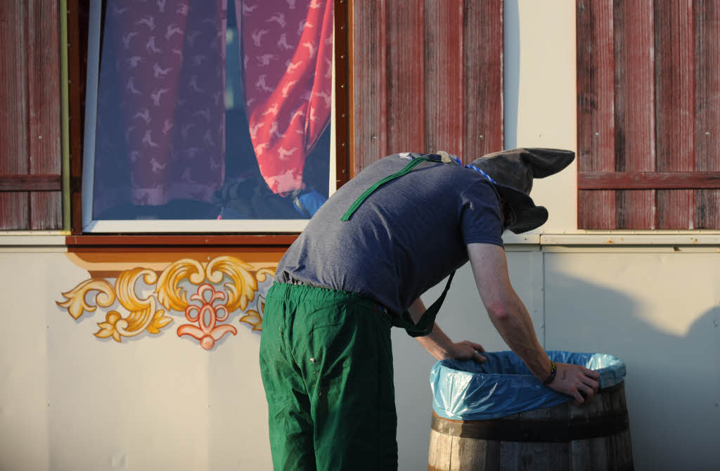 Ein betrunkener Mann steht vor einem Zelt auf dem Oktoberfest in München und übergibt sich in eine Tonne. Ein betrunkener Mann steht vor einem Zelt auf dem Oktoberfest in München und übergibt sich in eine Tonne.