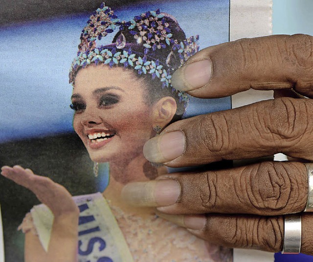 Ein Mann in Manila liest am Sonntag ei...ng mit dem Bild der neuen Miss World.   | Foto: AFP