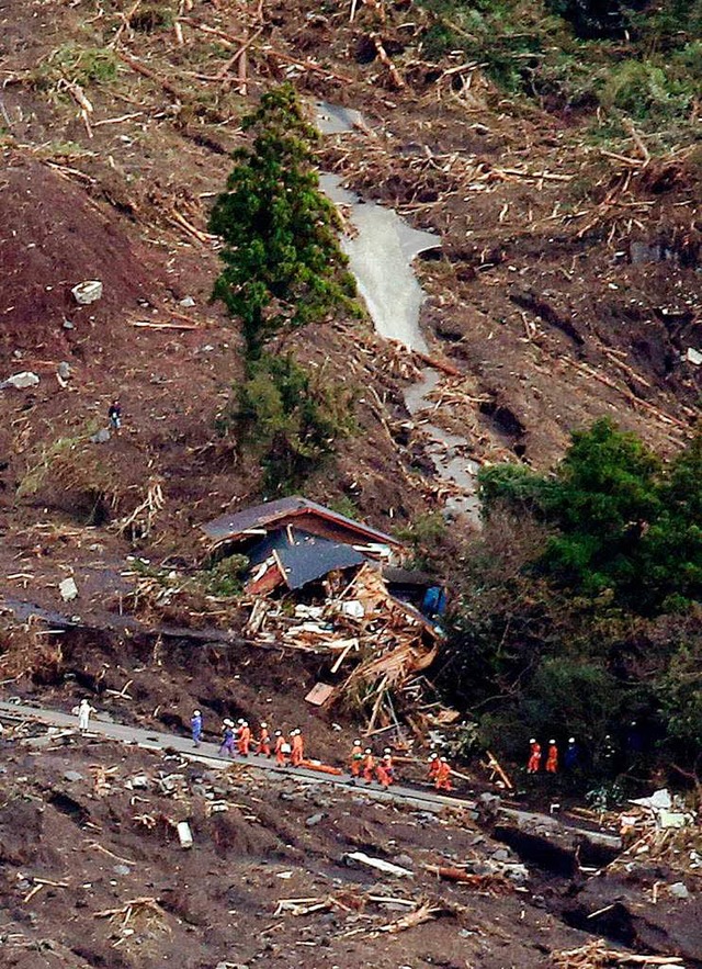 Helfer bahnen sich ihren Weg durch einen Erdrutsch auf der Insel Oshima.   | Foto: AFP