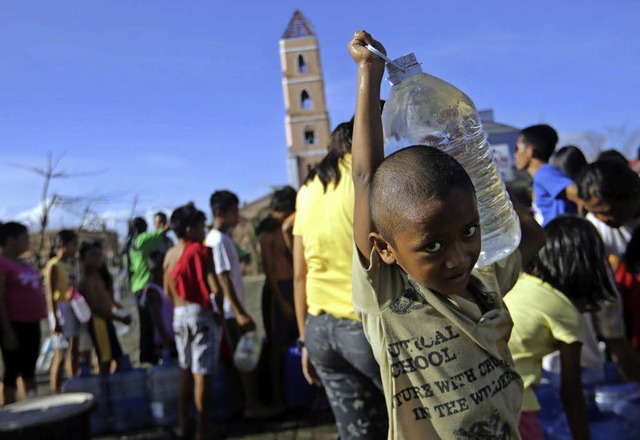 Ein Junge trgt eine Wasserflasche, die ihm Helfer gegeben haben.   | Foto: DPA