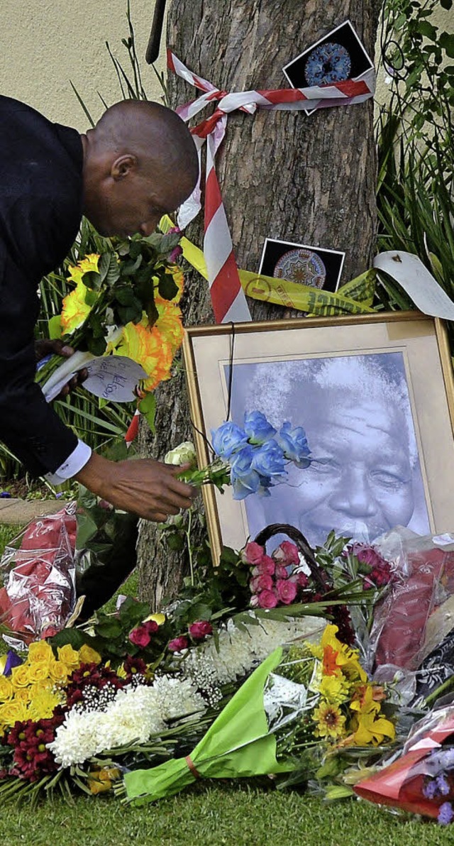 Ein Mann legt Blumen vor dem Haus Mandelas nieder.   | Foto: AFP