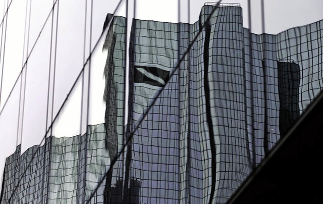 Die Zentrale der Deutschen Bank  spiegelt sich in Frankfurt in einer Fassade.  | Foto: dpa