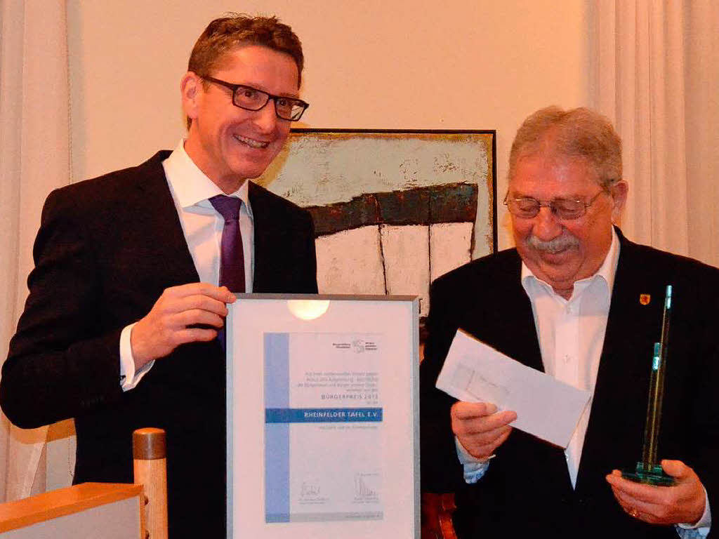 Rainer Liebenow bergibt Glasstele, Geldpreis und Urkunde an Helmut Moser.