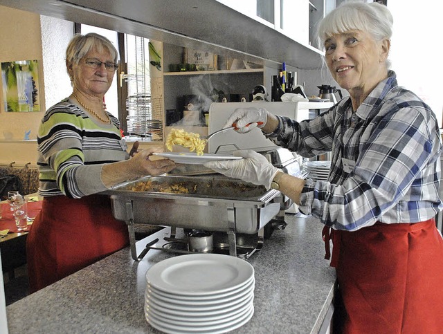 Hochbetrieb an der Theke, die Helfer geben das Essen aus und servieren am Tisch  | Foto: . Leony Stabla