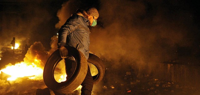 Ein Demonstrant in Kiew schleppt Reifen an, die spter entzndet werden sollen.   | Foto: DPA
