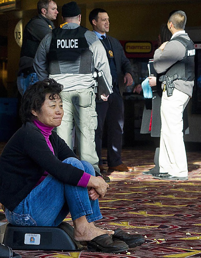 Eine Frau sitzt kurz nach der Tat  in ...obby des Einkaufszentrums und wartet.   | Foto: dpa