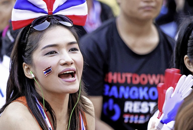 Eine Regierungsgegnerin trgt die Flagge Thailands aus ihrer Wange.   | Foto: DPA