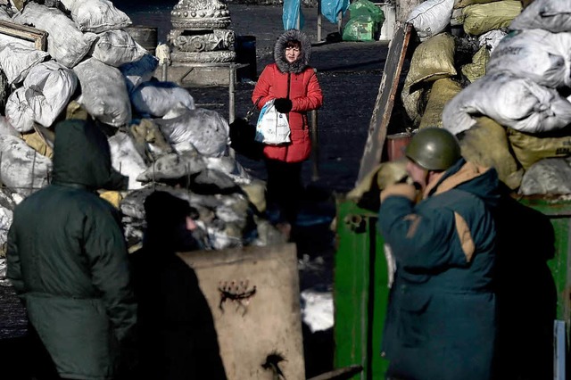 Eine Frau steht vor einer Straensperre der Opposition in Kiew.  | Foto: AFP