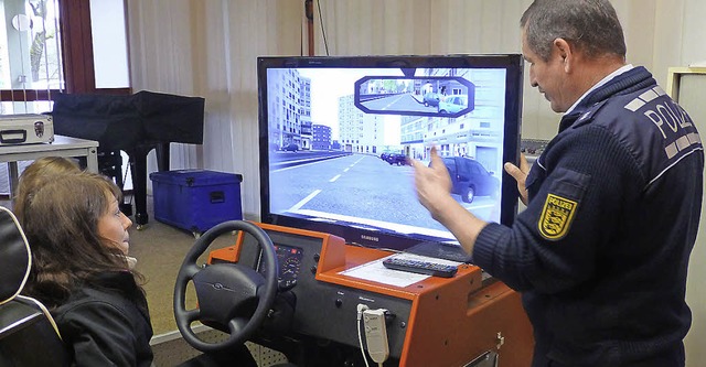 Polizist Waldemar Weber erklrt Lisa B...e im Einzelhandel) den Fahrsimulator.   | Foto: Rudolf-Eberle-Schule