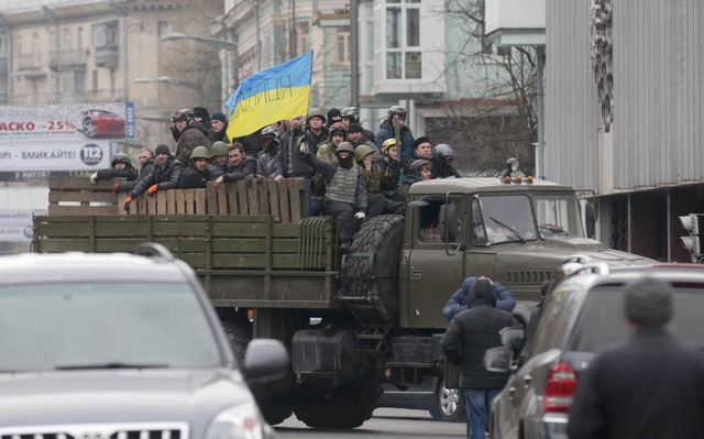 Regierungsgegner schwenken die Nationa...trfahrzeug herab im Zentrum von Kiew.  | Foto: dpa