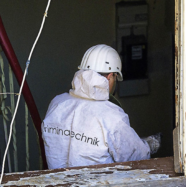 Ein Polizist untersucht Brandspuren in der Wohnung.   | Foto: dpa