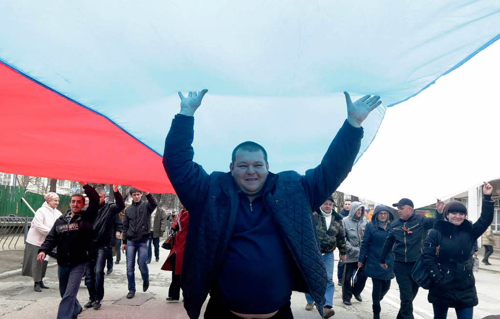 Pro-russische Aktivisten marschieren mit einer riesigen Russland-Flagge durch Simferopol.