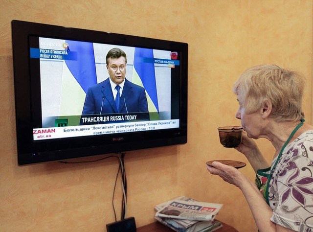 Eine Frau auf der Krim hrt sich die E...ukowitsch im russischen Fernsehen an.   | Foto: dpa