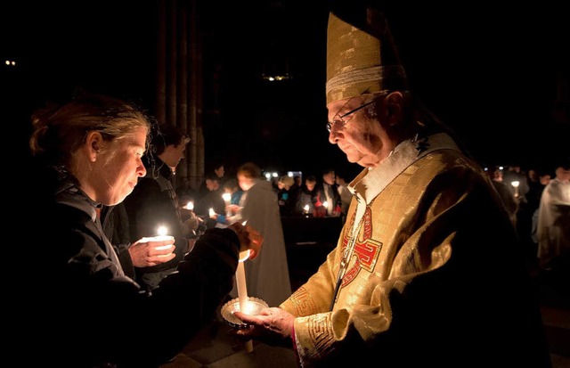 Erzbischof Robert Zollitsch hlt in de...am im Mnster  eine Kerze in der Hand.  | Foto: dpa