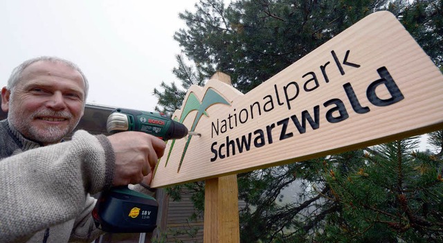 Direktor Wolfgang Schlund befestigt ein Nationapark-Schild.  | Foto: dpa