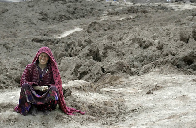 Eine berlebende sitzt weinend auf dem...er dem ihr Heimatdorf begraben liegt.   | Foto: AFP